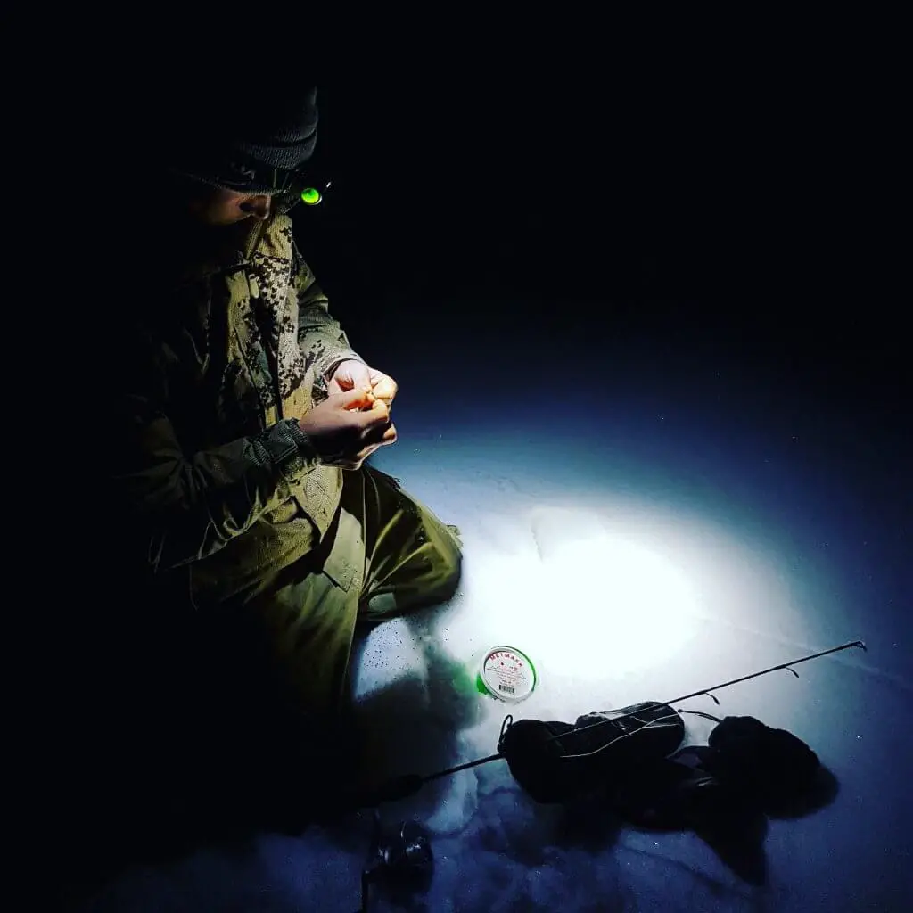 Person wearing best headlamp for fishing at night preparing to Ice Fish
