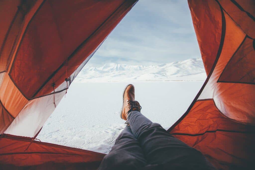 Person relaxing in an open tent on a frozen lake