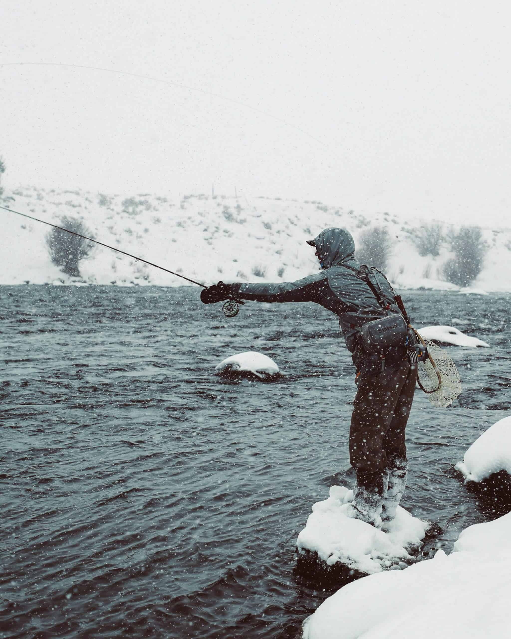 Man Fishing wearing some of the best fly fishing gloves in the snow