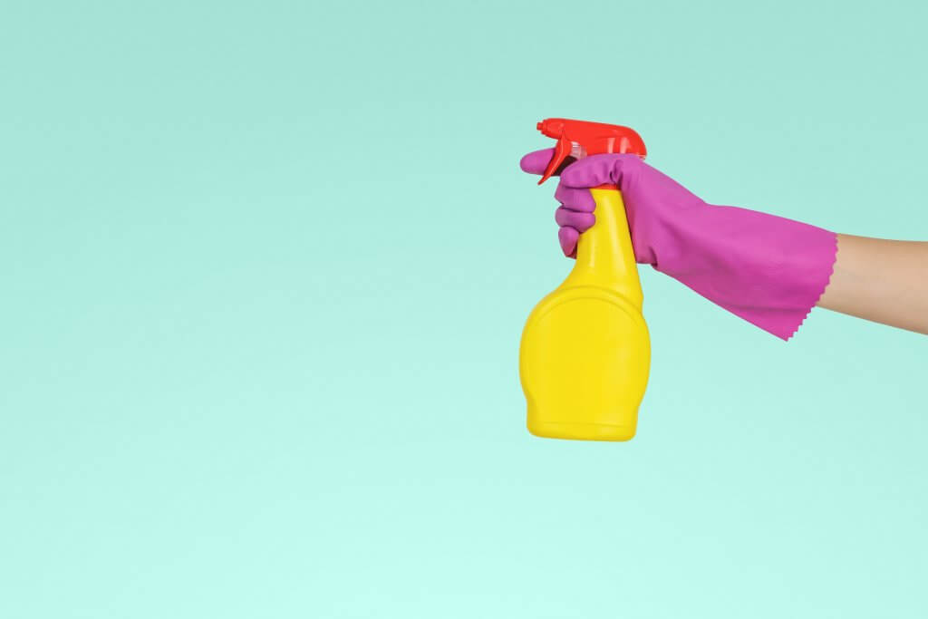 hand with purple glove holding spray