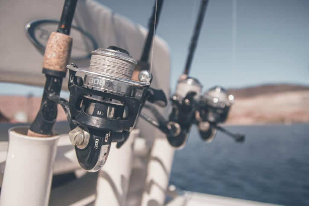 three fishing rods and reels in rod holders on a boat
