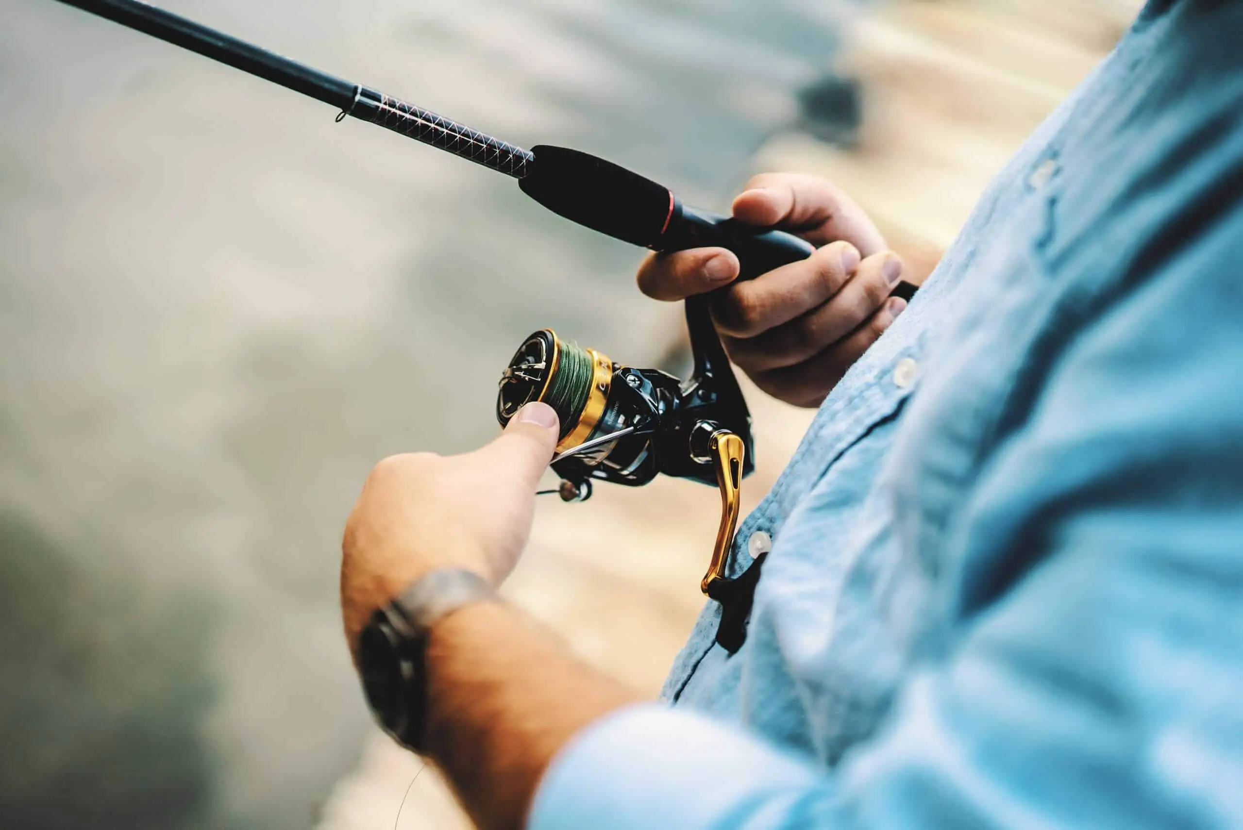 Man in blue shirt using one of the best spinning reel under 50$ in gold