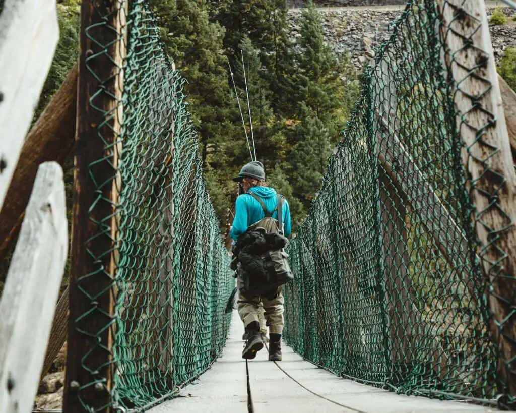 Man wearing one of the best fishing backpack walking on a bridge