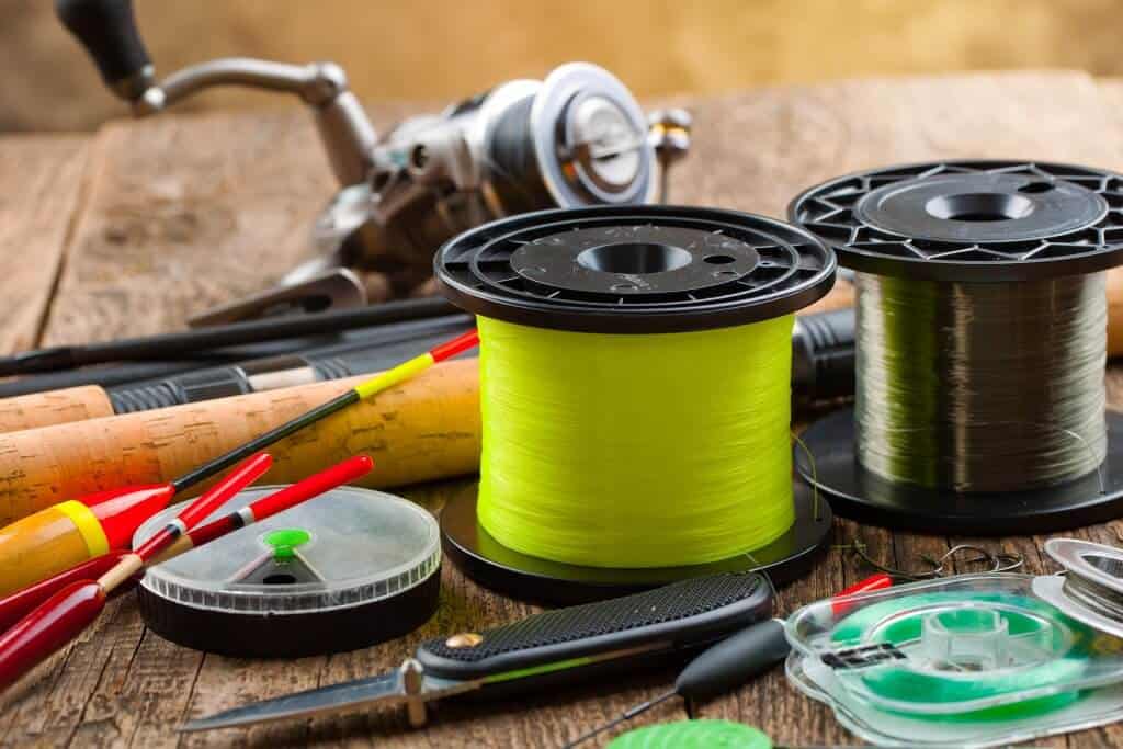 Two rolls of fishing line on a table next to other fishing gear