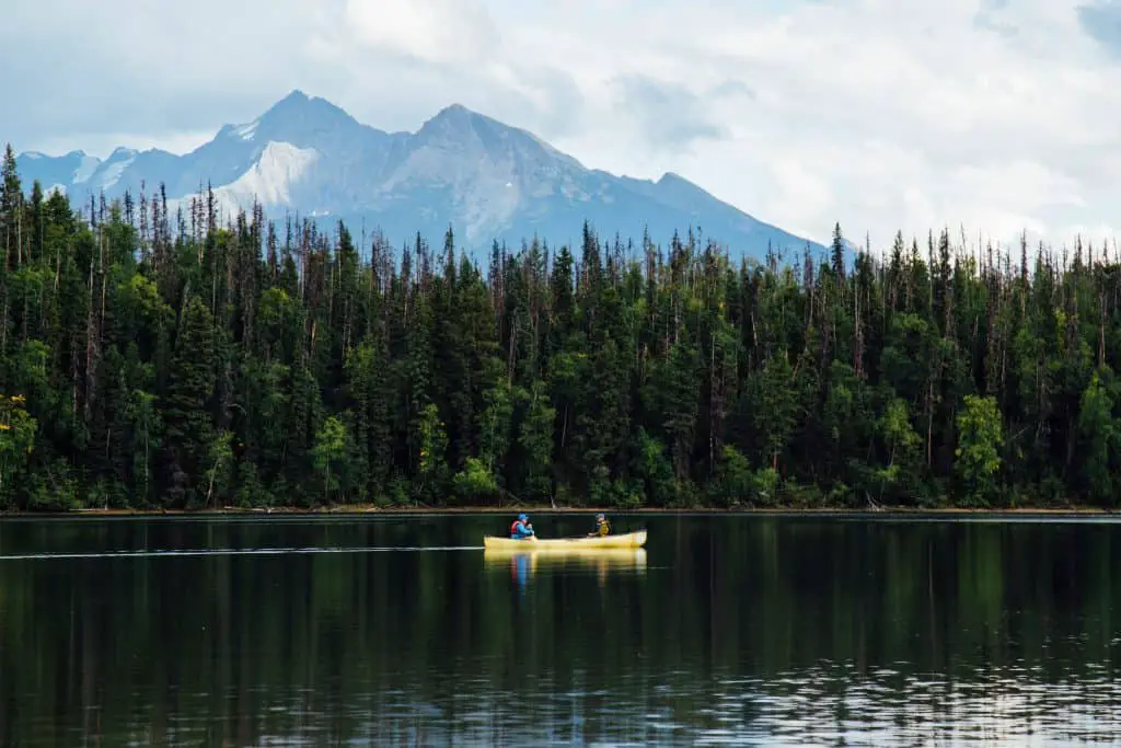 Two fishermen on a lake sitting in one of the best tandem fishing kayaks on their way a fishing spot