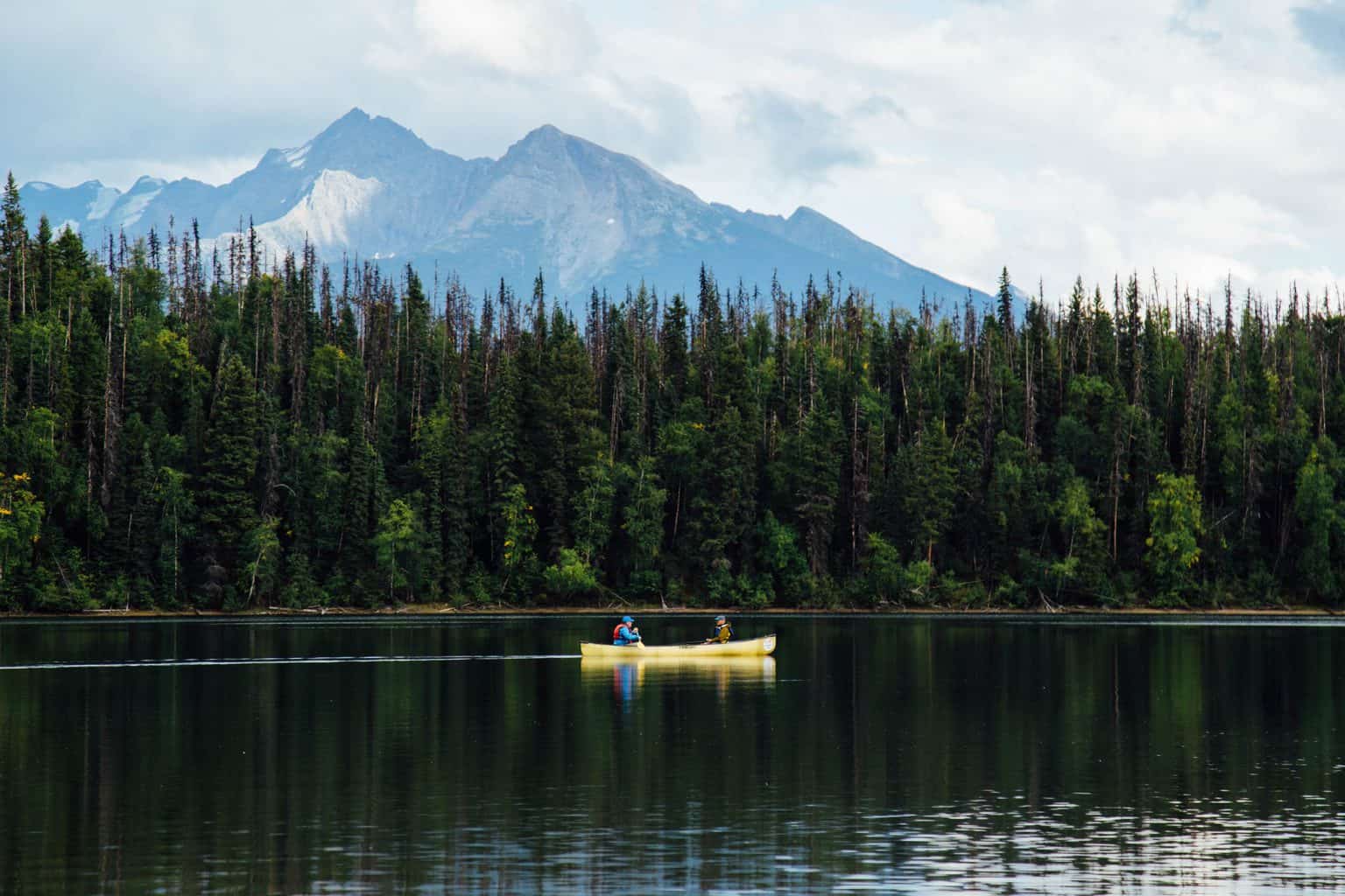 Two fishermen on a lake sitting in one of the best tandem fishing kayaks on their way a fishing spot