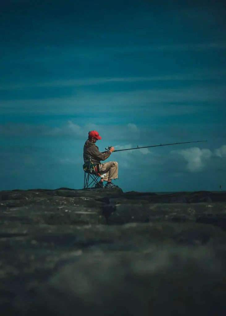 Fishing man sitting on a peer on one of the best portable fishing chairs