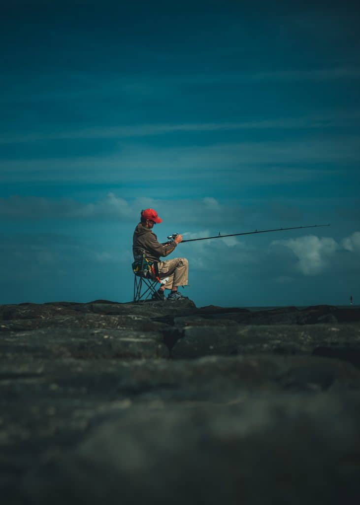 Fishing man sitting on a peer on one of the best portable fishing chairs