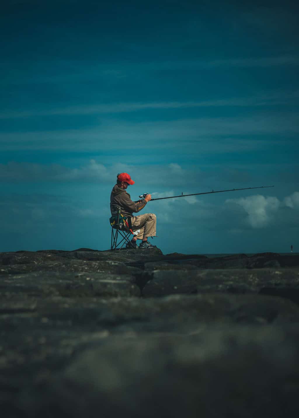 Fishing man sitting on a peer on one of the best portable fishing chairs
