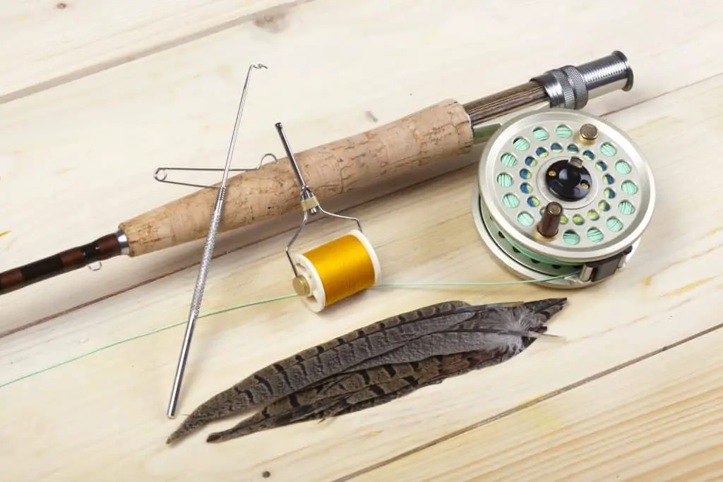 One of the best 5 weight fly rods on a wooden surface with feathers next to it