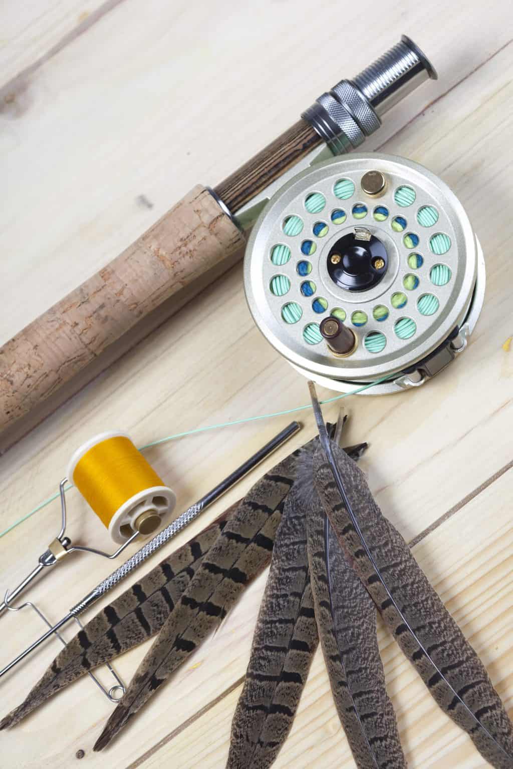 a fly fishing rod and reel lying on a wooden surface. also some feathers. Will fishing line melt or burn?