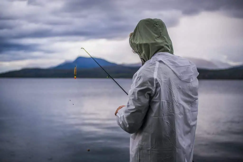 a man fishing in the rain wearing a raincoat