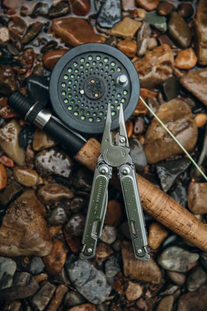 leatherman next to a fly rod