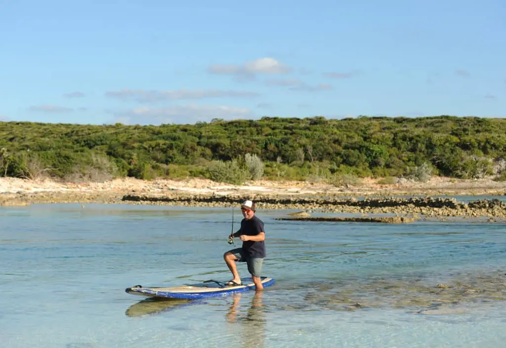 Man stepping off one of the best fishing paddle boards while fishing in scenic tropical destination