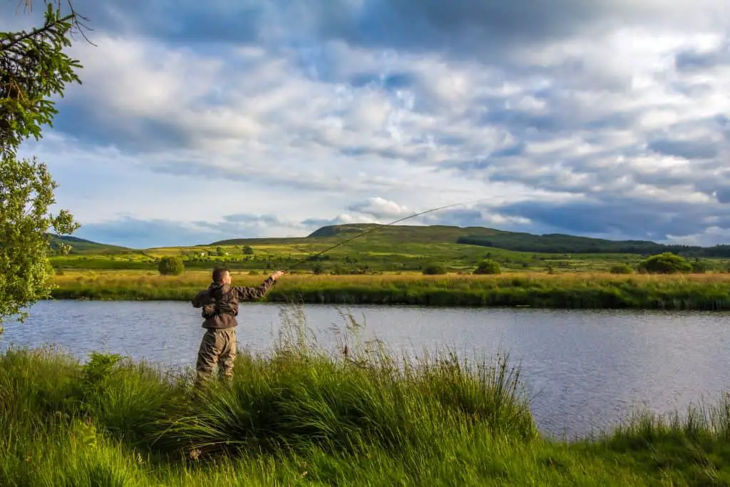 A fisherman fly fishing for crappie in the evening sun on the Blackwater of Dee, Galloway, Scotland