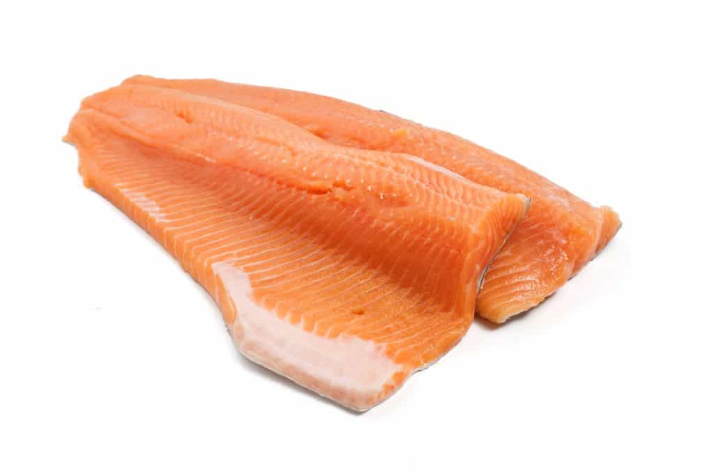 two salmon trout fillets over white background