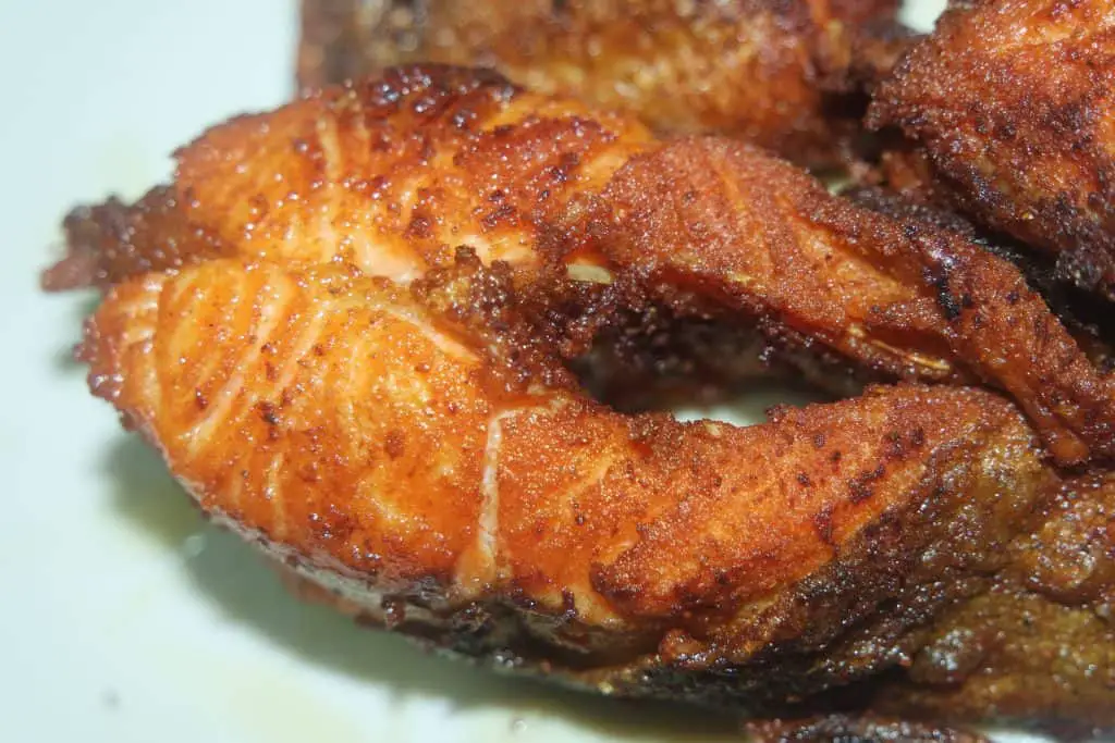 Spicy and crunchy barbecue of fried fish fillet on a white background. Homemade grilled trout fish steaks