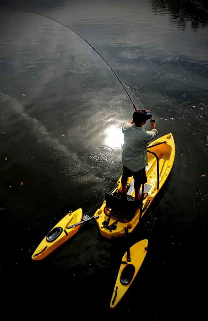 Man with brown hair fly fishing in a lake in one of the best fishing kayak under 600