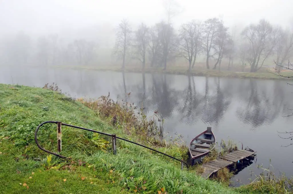 autumn time mist and boat in rural river