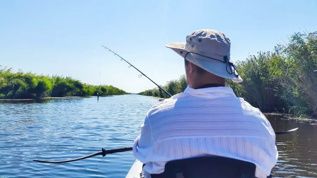 Man fishing on a river who had to decide between going with a fishing kayak vs canoe - what are the differences?