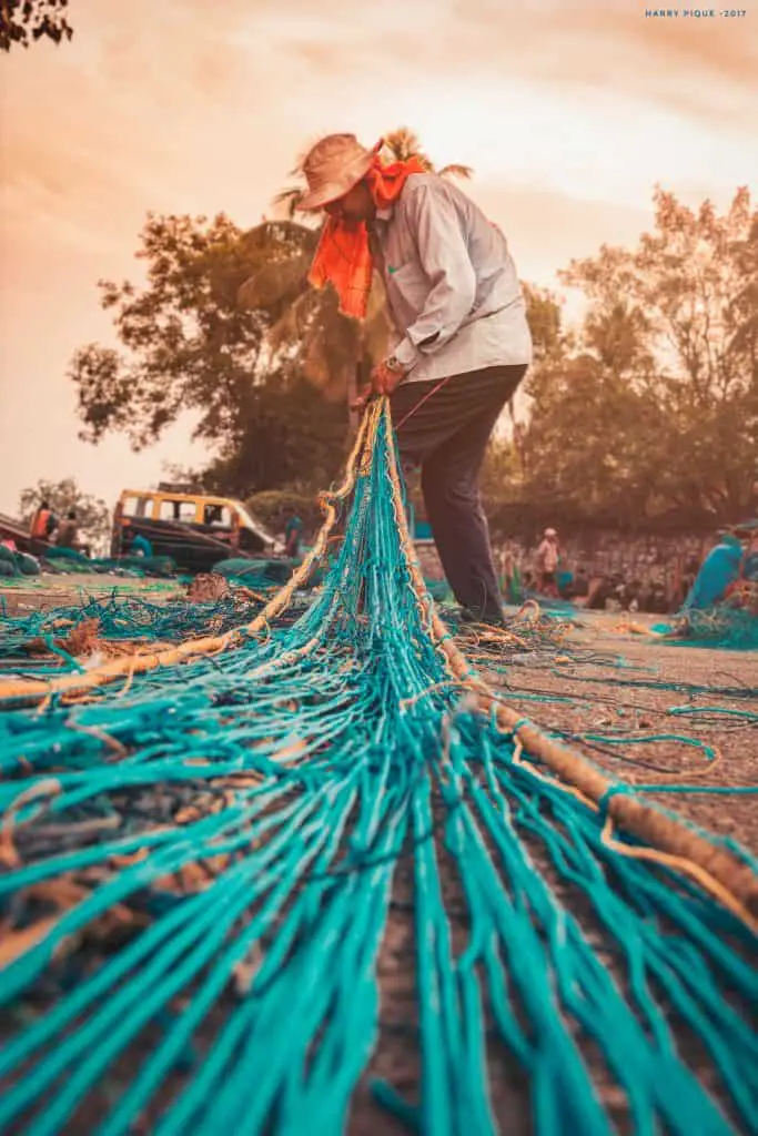 A man working on his net on a beach