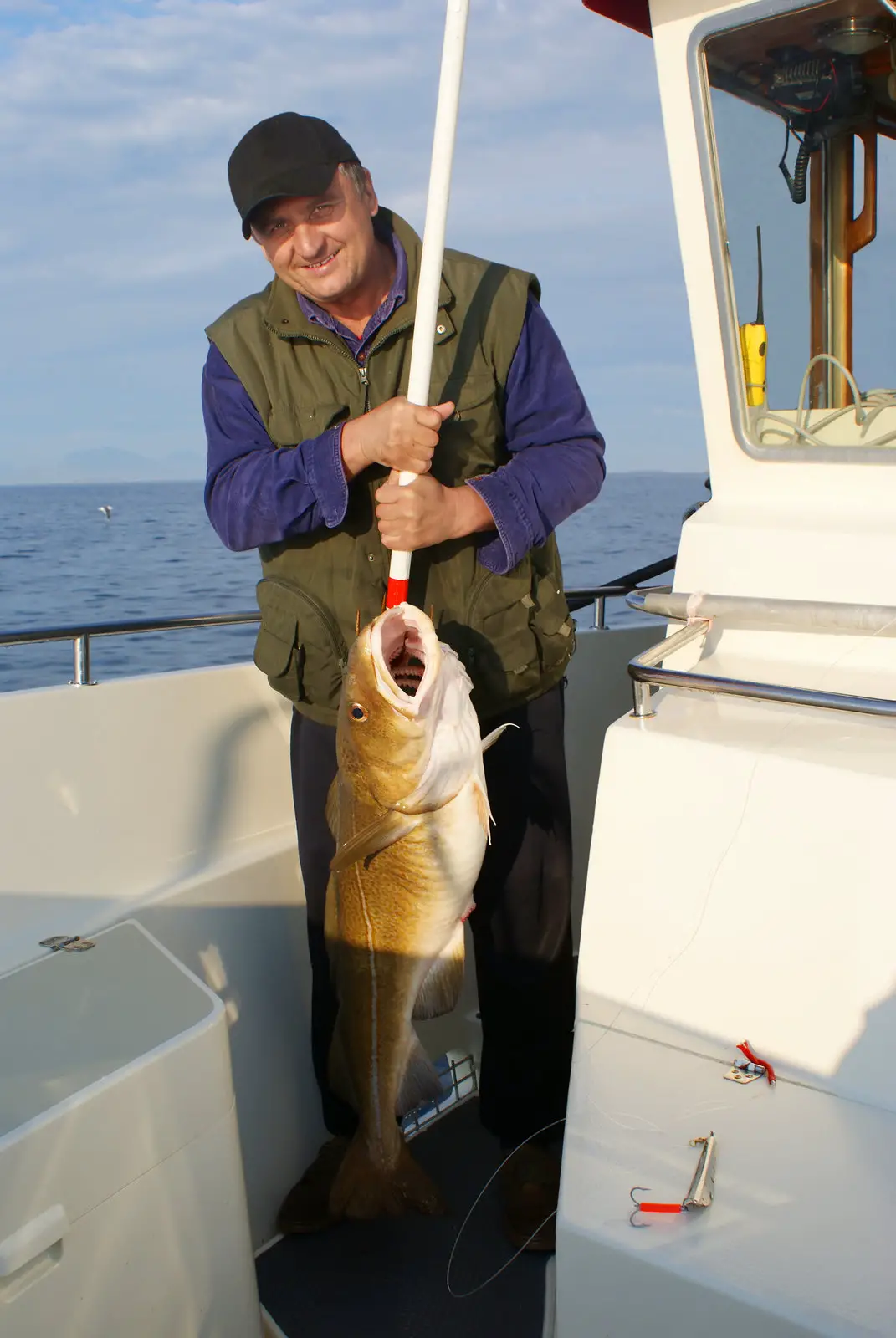 a man using a gaff fishing hook to reel in his fish and present it